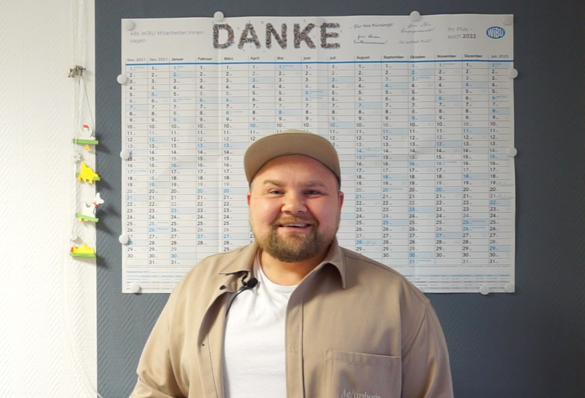 Thomas steht vor einer großen Pinnwand mit einem Jahreskalender