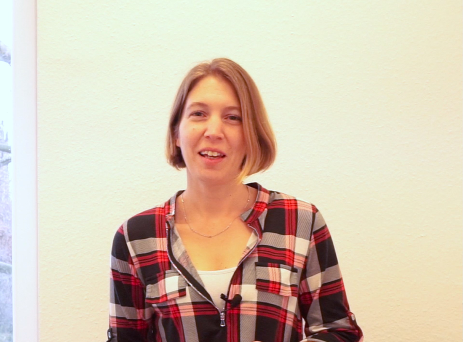 Meike Prasse steht vor einer weißen Wand und schaut in die Kamera