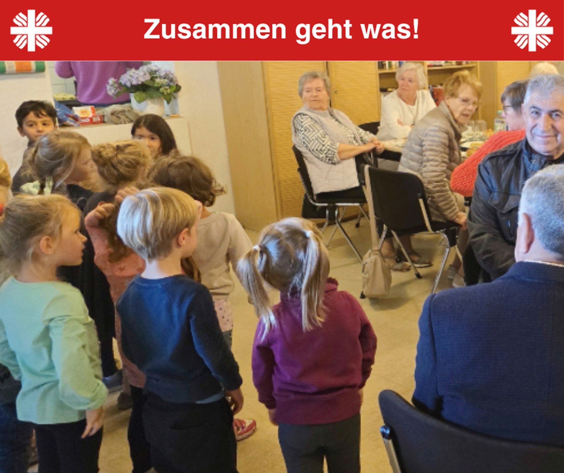 Rechts im Bild sitzen sechs Senior*innen und drehen sich um zu neun Kindern, die links im Bild stehen